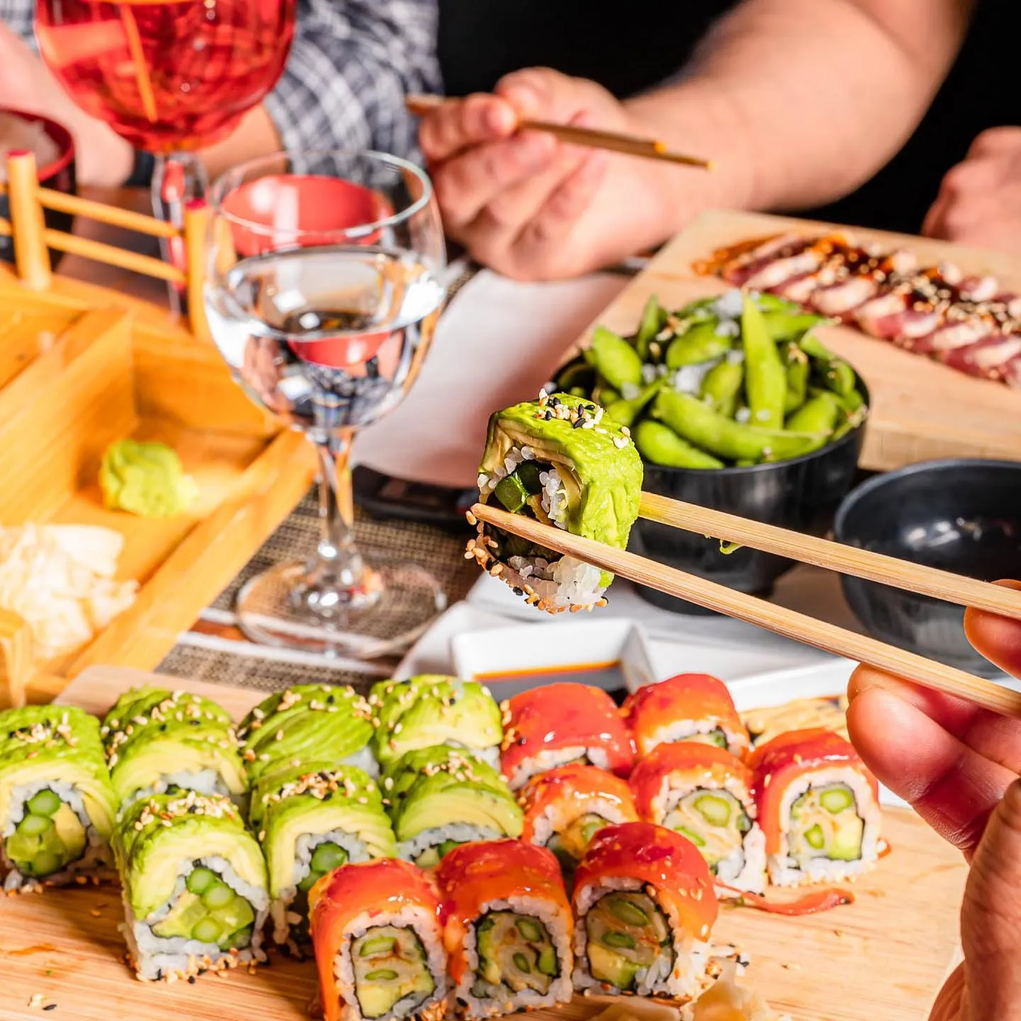 Gedeckter Tisch mit Sushi-Rollen, Edamame und Wein