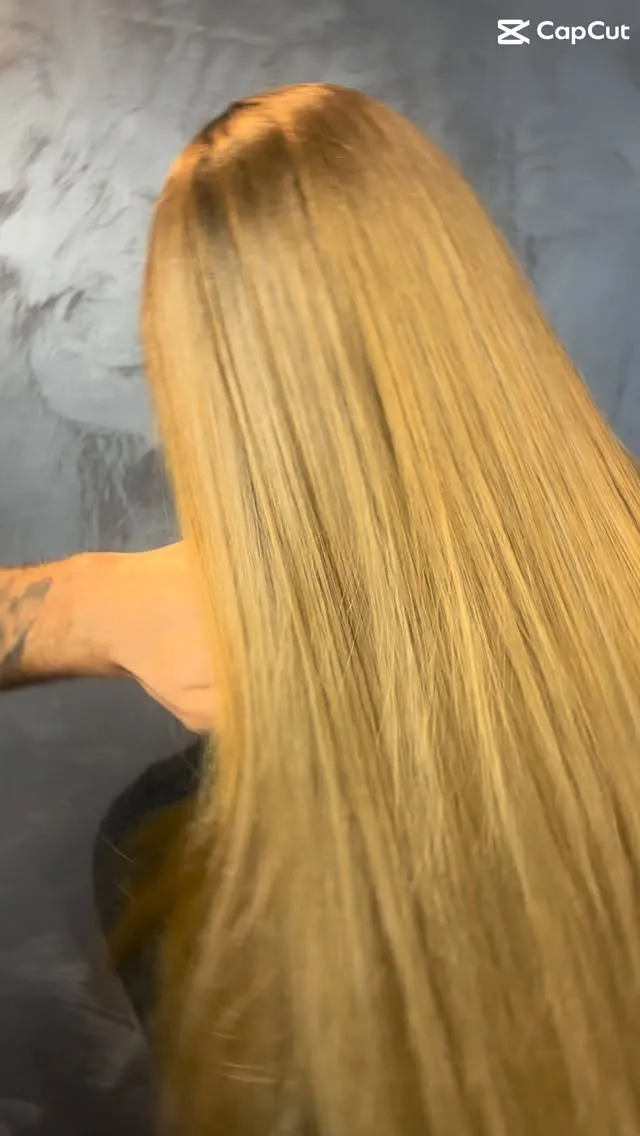 Sehr langes, glatt geföhntes Blond von hinten vor der grauen Spachtelwand des Salons; oben rechts steht ein eingeblendetes Schnittprogramm-Wasserzeichen.