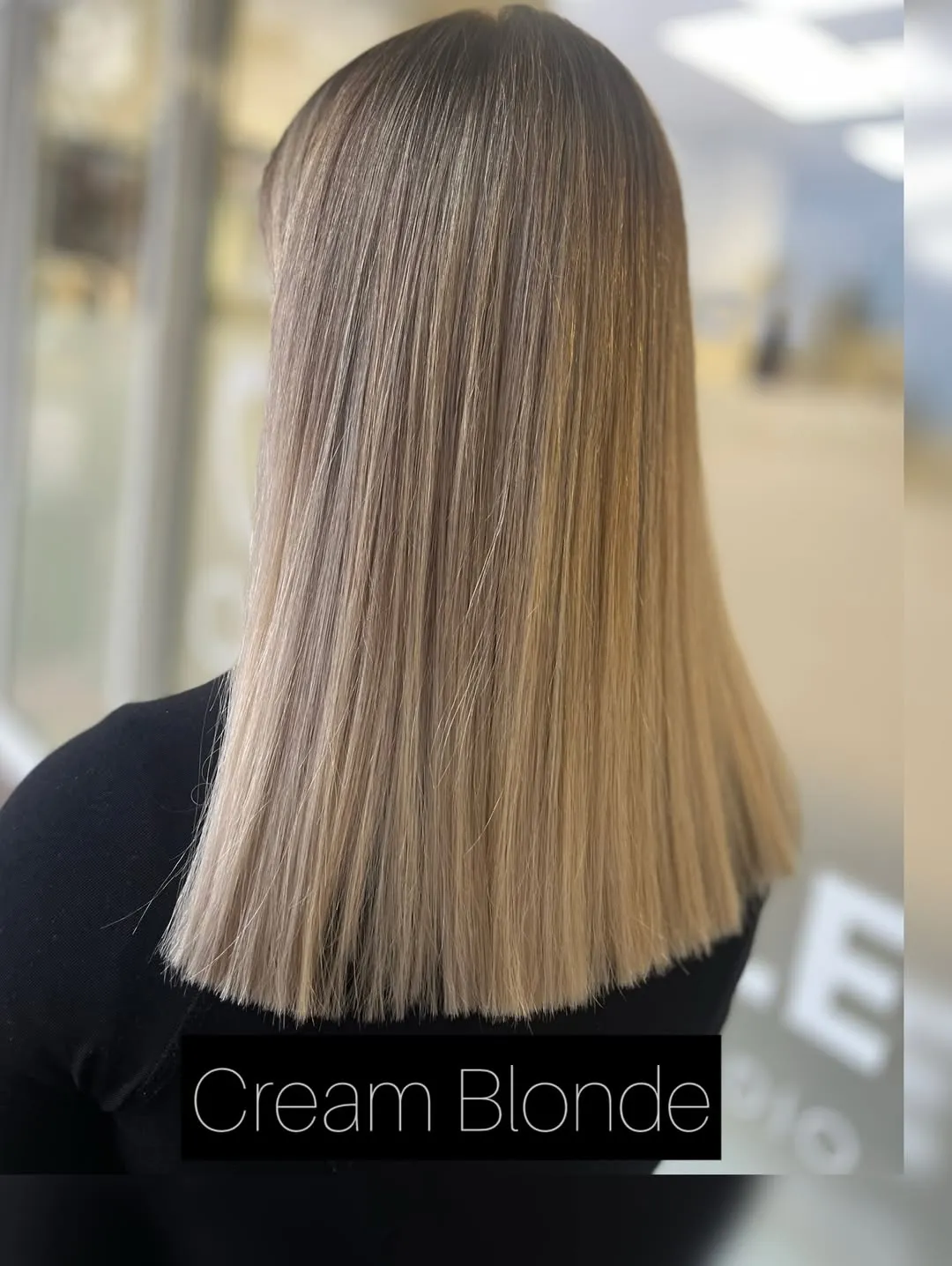 Schulterlanges Cremeblond mit dunklerem Ansatz, stumpf geschnitten und glatt gestylt, von hinten fotografiert.
