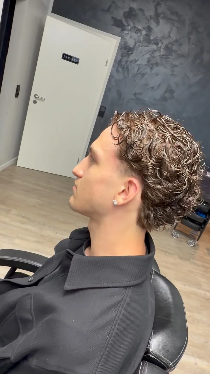 Herren-Dauerwelle mit definierten Locken und kurz ausrasierten Seiten, Seitenansicht im Salon.
