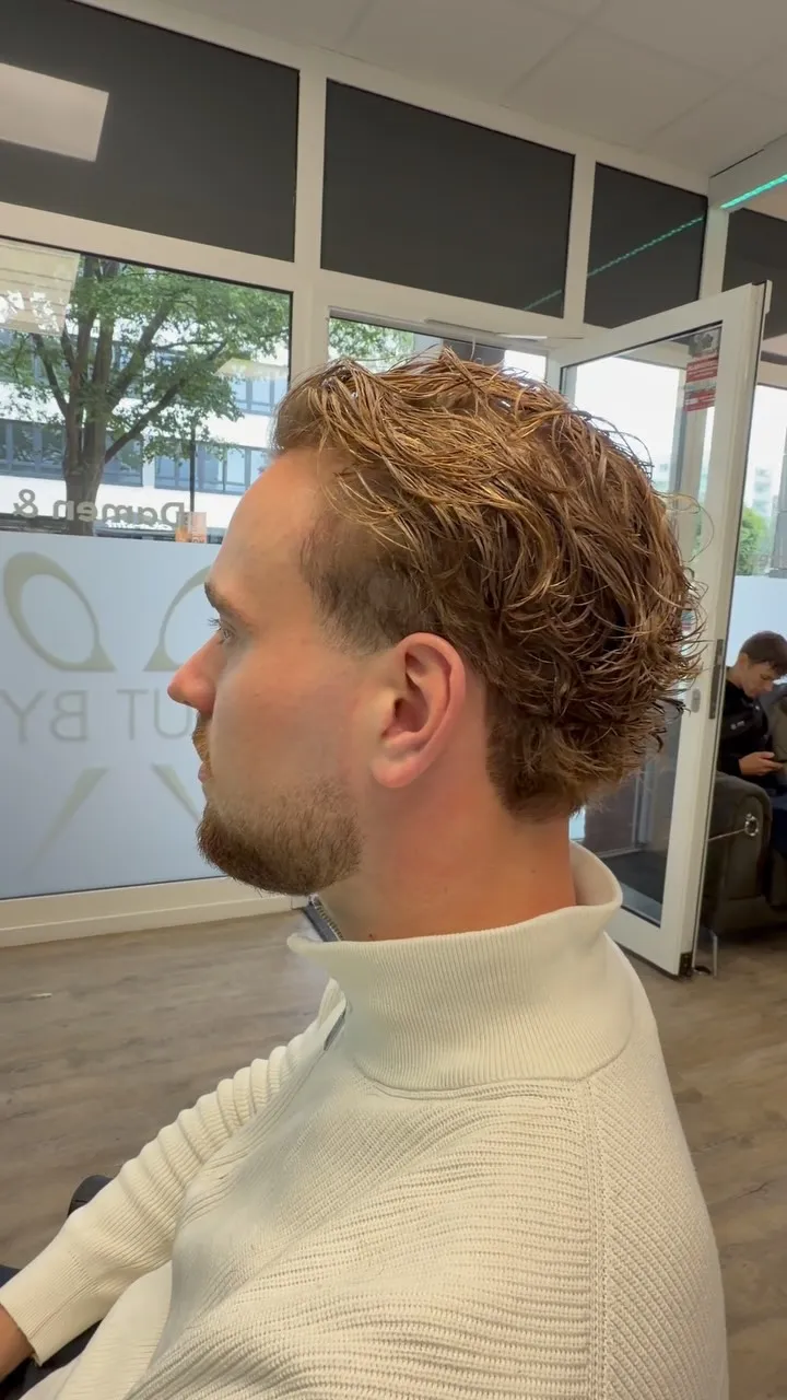 Herren-Dauerwelle: lockiges blondes Deckhaar über kurzen Seiten, Seitenansicht im Salon.