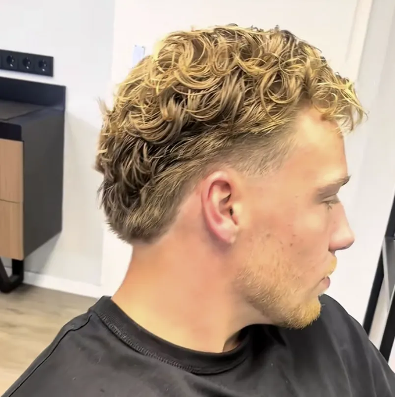 Nachher: dieselben blonden Locken definiert geschnitten und gestylt, an Seiten und Nacken zu einem Taper ausrasiert.