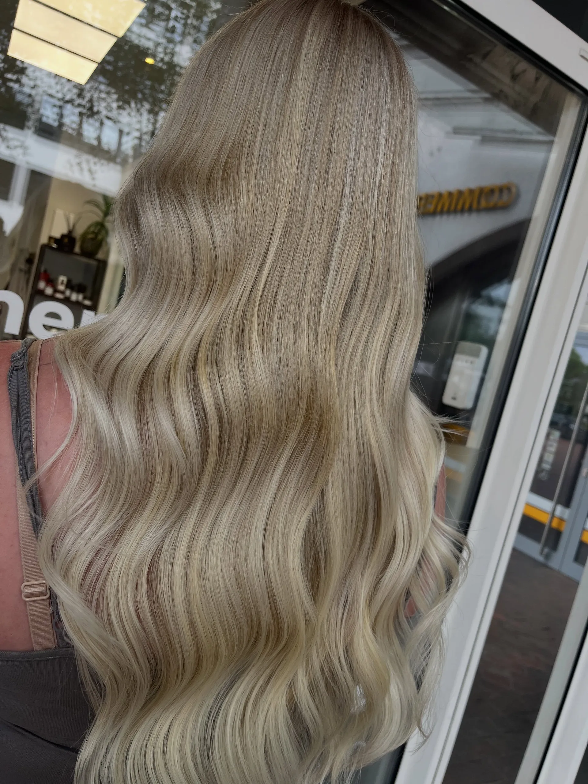 Sehr lange, große Wellen in hellem Champagnerblond, von hinten vor der Schaufensterfront.