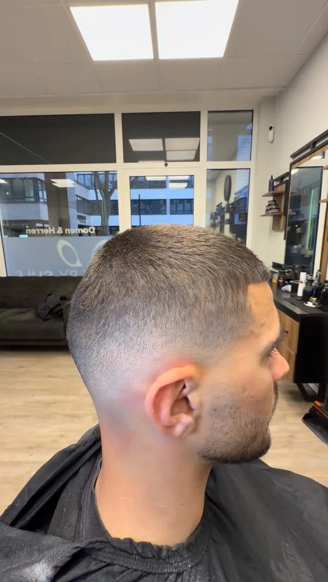 Sehr kurzer Herrenschnitt mit hoch auslaufendem Skin Fade und konturiertem Bart, Seitenansicht.