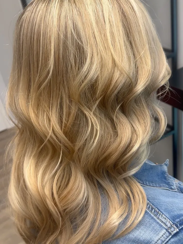 Goldblonde Haare von hinten, auf Schulterlänge in gleichmäßige Wellen gelegt.