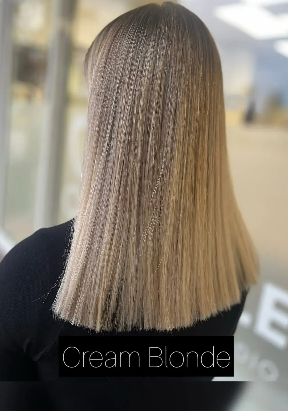 Schulterlanges Cremeblond mit dunklerem Ansatz, stumpf geschnitten und glatt gestylt, von hinten fotografiert.
