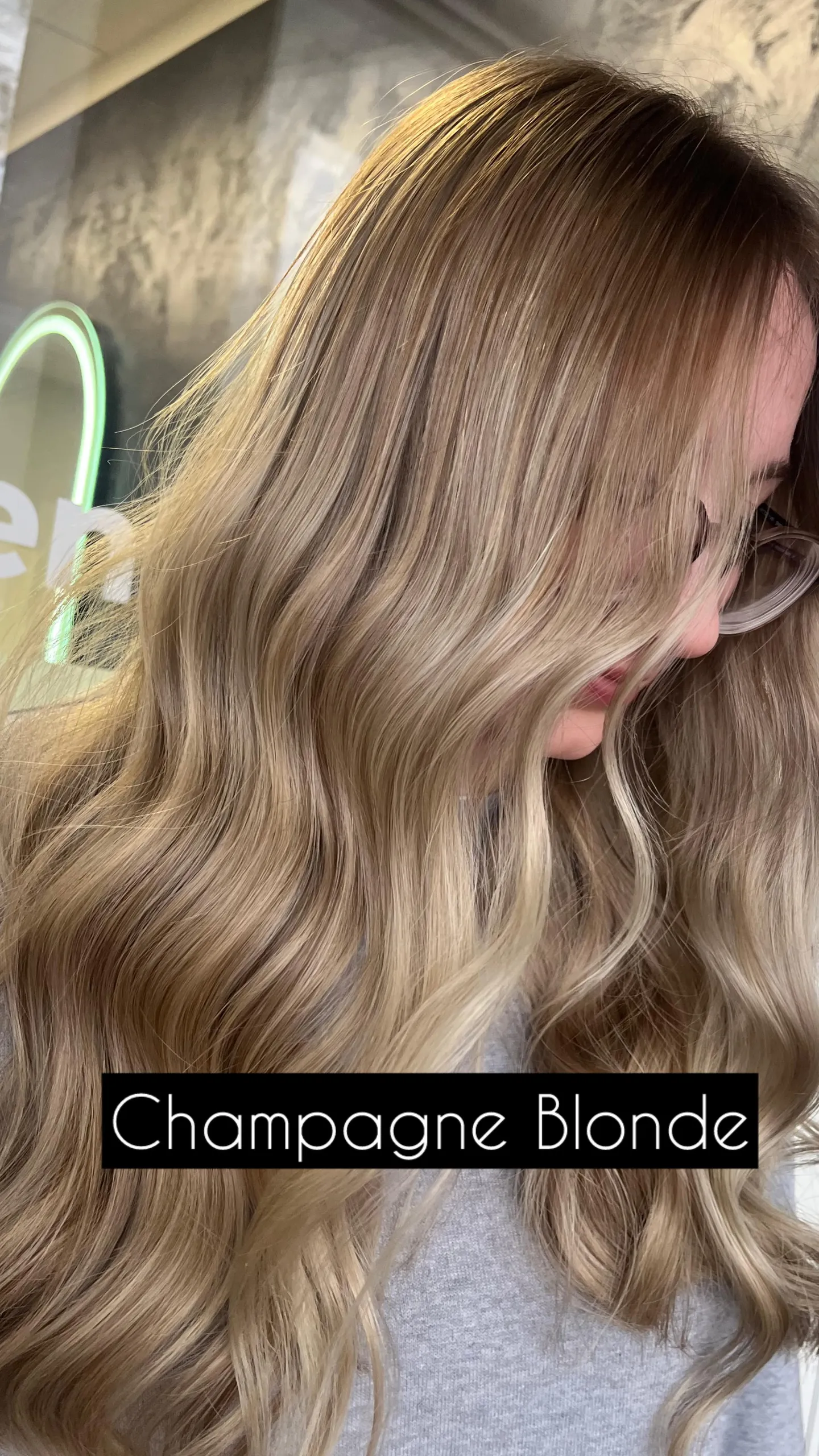 Lange Balayage-Wellen in hellem Champagnerblond, seitlich fotografiert; unten steht die eingeblendete Bildunterschrift „Champagne Blonde“.
