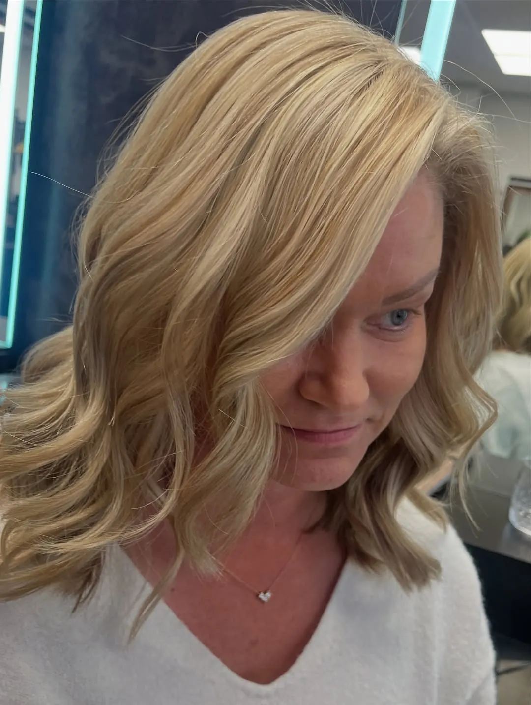 Blonder Long Bob auf Schulterhöhe mit weichen Wellen und hellen Strähnen rund ums Gesicht.