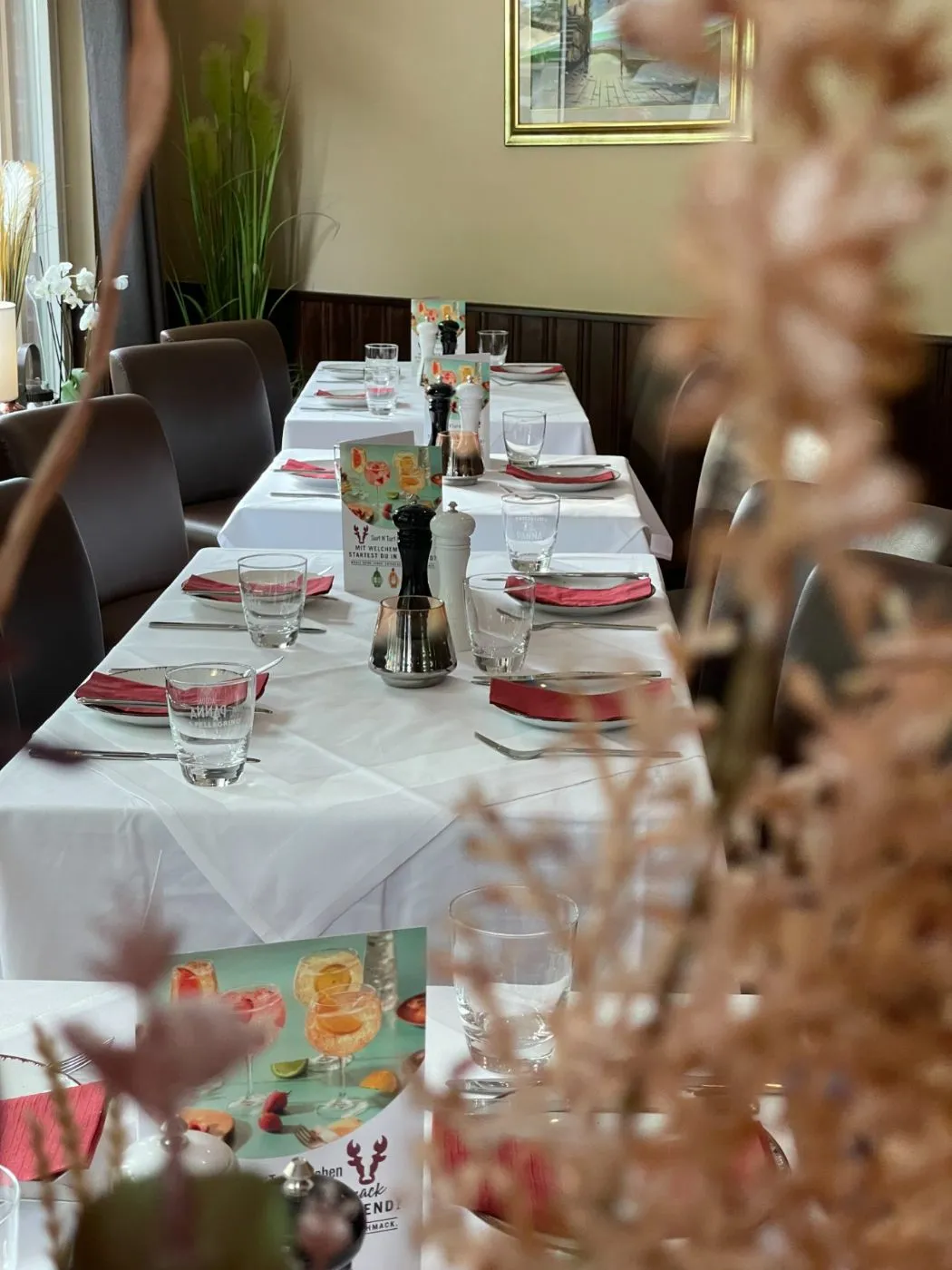 Eingedeckte Tafel mit Blumendeko im Vordergrund, fotografiert durch getrocknete Pampasgräser.